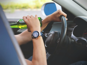 A person consuming beer while driving