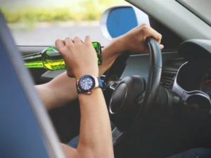 A person drinking beer while driving