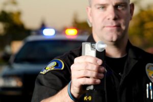 A police officer holding a breathalyzer with someone about to get a DUI.