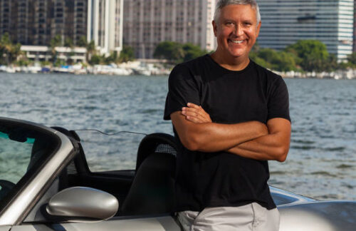 A middle-aged man standing by a borrowed silver convertible who is driving with an Oregon non-owner insurance policy.