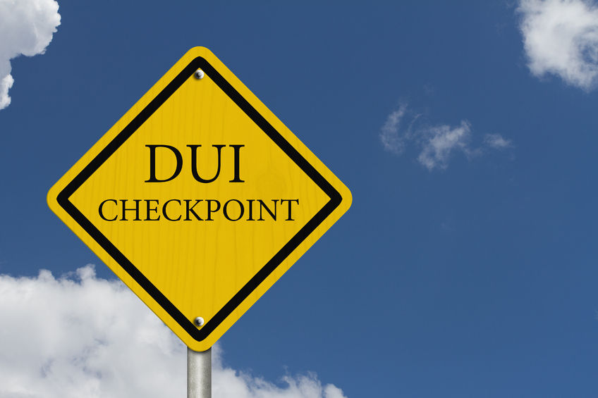 A yellow DUI checkpoint sign in Florida with blue sky and clouds in the background.